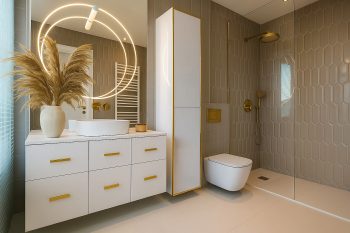 Glänzender Bad-Hochschrank Monako 40cm mit goldenen Details neben Dusche und Waschplatz