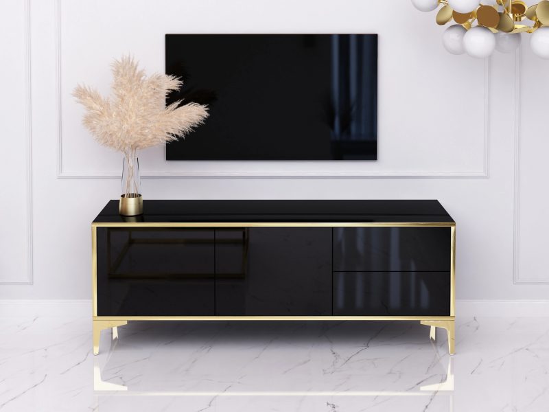 TV-Lowboard Monako 136cm Schwarz Hochglanz mit goldenen Akzenten im Wohnzimmer mit Fernseher.