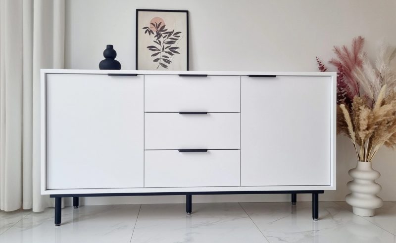 Weiße Kommode Cala 154cm mit schwarzen Griffen, Frontansicht im modernen Wohnzimmer